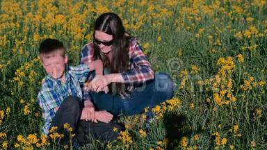 母子俩玩黄花坐在草地上.. 家庭出游。